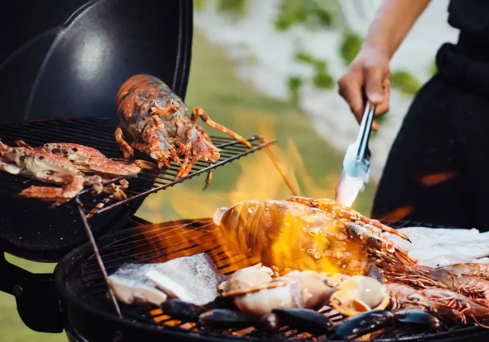 Professional private chef grilling fresh lobster, prawns, fish, and seafood over an open flame for a luxury private BBQ experience in Dubai.